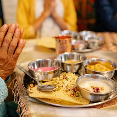 Close-up of a traditional Indian meal with hands in prayer, reflecting cultural dining rituals.